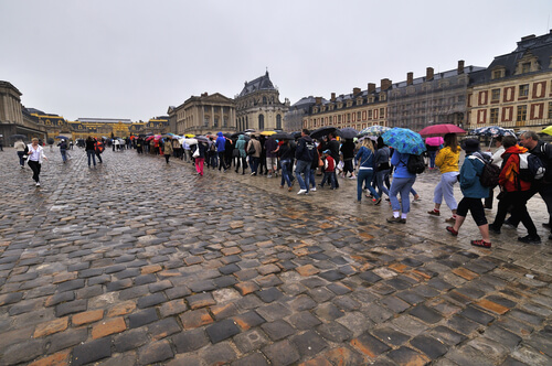 Sob chuva, turistas esperam na fila para entrar em Versailles. 